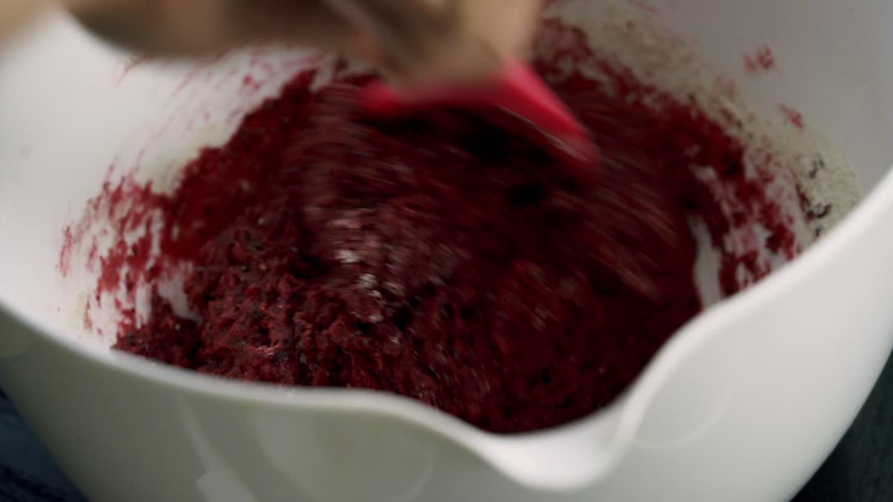 mezclando la masa de remolacha roja en un cuenco blanco para hacer el muffin de remolache de chocolate de terciopelo rojo del día de san valentín