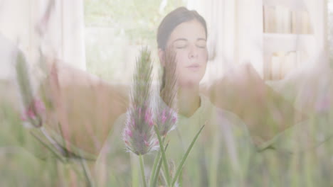 animation of meadow over woman exercising and meditating at home