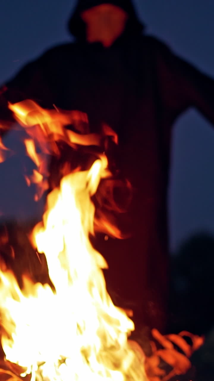 Angry witch near the fire. Terrible demon standing by the fire Vertical video