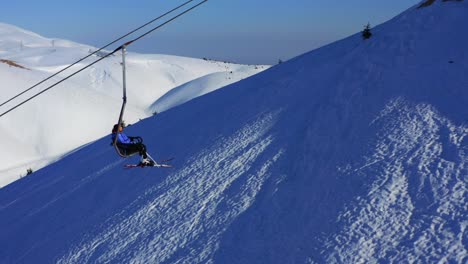 Aerial-shot-of-a-woman-on-a-chairlift-in-a-clear-day