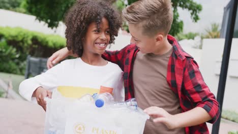 un video de dos escolares felices y diversos recogiendo plástico reciclado y abrazándose en el patio de la escuela.