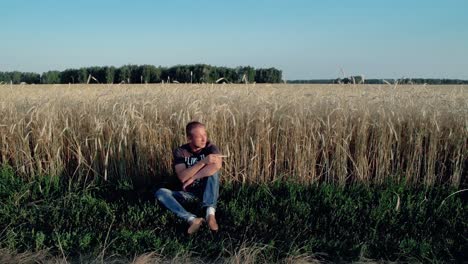 Young-man-sitting-near-the-field-of-rye