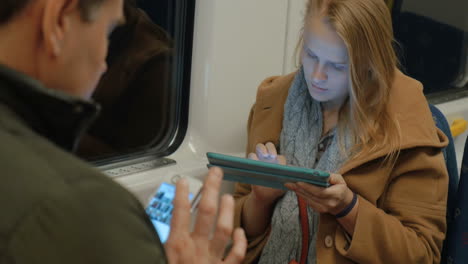 frau im u-bahn-zug, die auf einem tablet schreibt