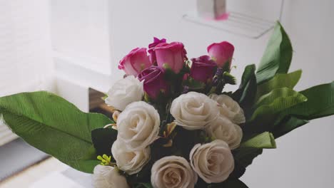 mano femenina poniendo una carta con la inscripción gracias en el ramo de flores