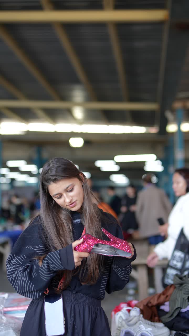 Donna che guarda tacchi alti rosa al mercatino delle pulci