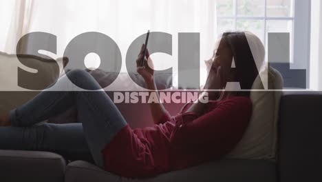 Animation-of-social-distancing-text-over-woman-using-smartphone-at-home