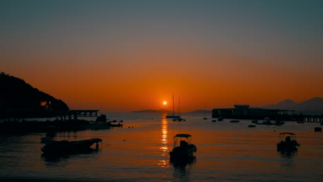 Time lapse of a little harbor of a little fisher village during a beautiful sunset. Few boats are going back to dock.