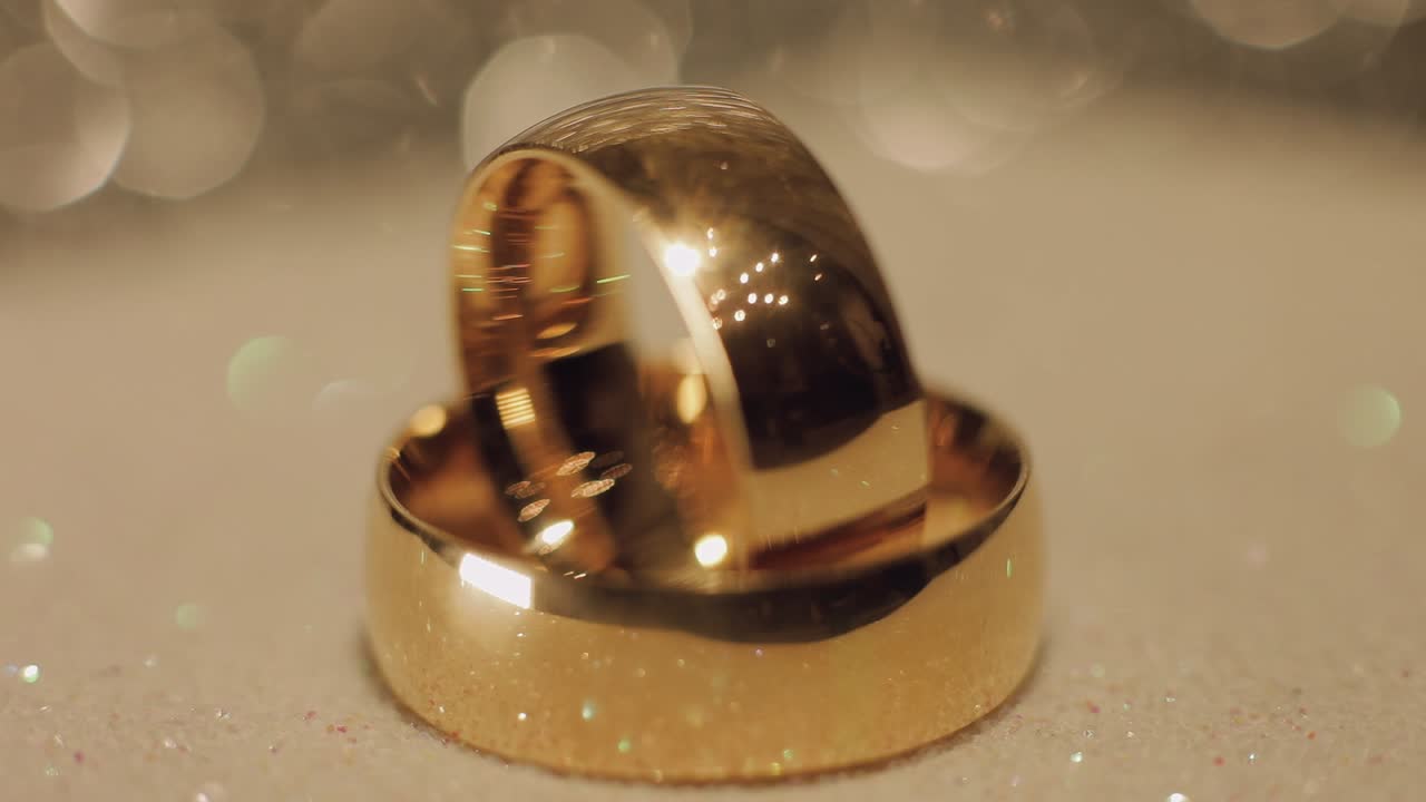 Wedding gols rings lying on shiny glossy surface. Shining with light. Close-up