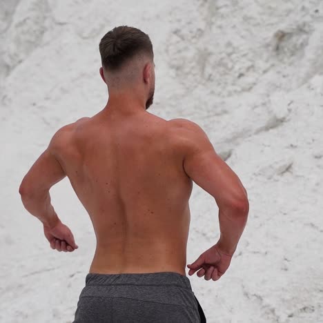 young bodybuilder poses in nature