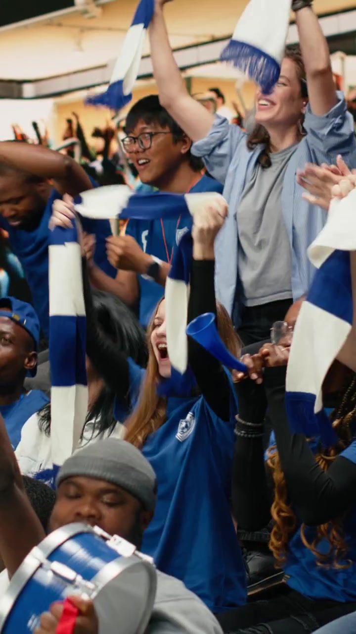 Video vertical: Líder de cánticos de fútbol soplando una vuvuzela mientras los aficionados azules responden.