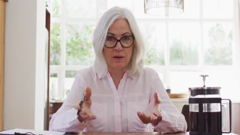 retrato de una mujer mayor con gafas hablando mirando a la cámara mientras trabaja desde casa