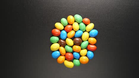 top view: coloful candies shake on a black table (stop motion)