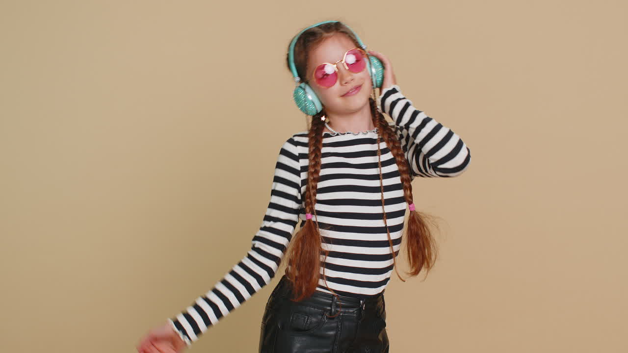 Happy smiling preteen child girl listening music dancing disco fooling around having fun indoors