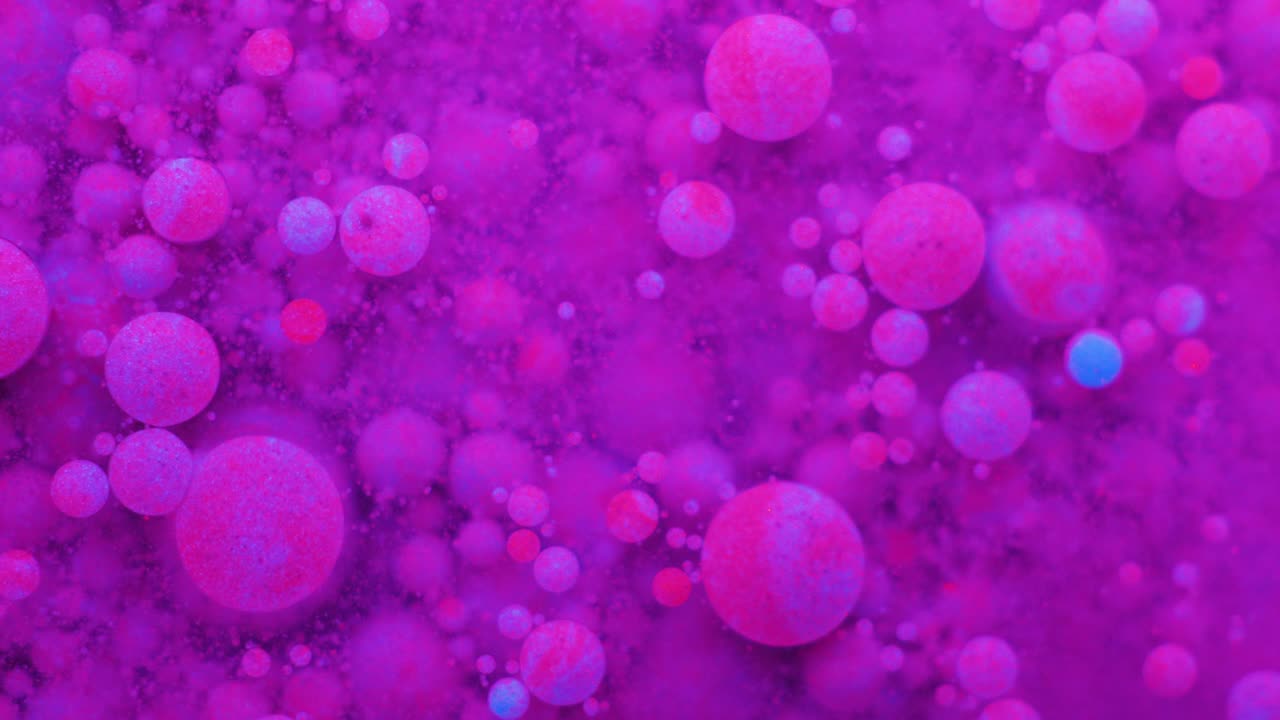 Slow Motion Bright Neon Color Bubbles Oil Beautiful Fluorescent Paint Sparkling Color Moving Multicolor Close up. Acrylic Neon Paint. Fantastic Surface. Abstract Colorful Transformation Gravitation.