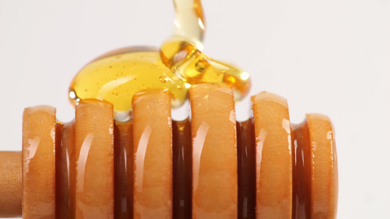ホワイトバックグラウンドに蜂蜜が滴り落ちる 健康なオーガニック厚い蜂蜜 クローズアップ 甘い蜂蜜デザート 4k
