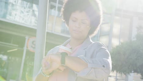 plus size biracial woman checking smartwatch and drinking coffee in city