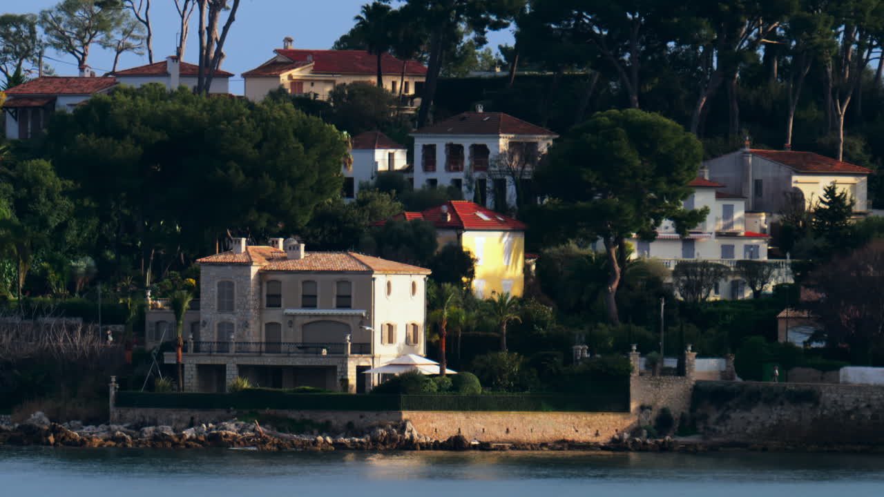 Different buildings surrounded by trees on the coast, near the sea in Cannes, France