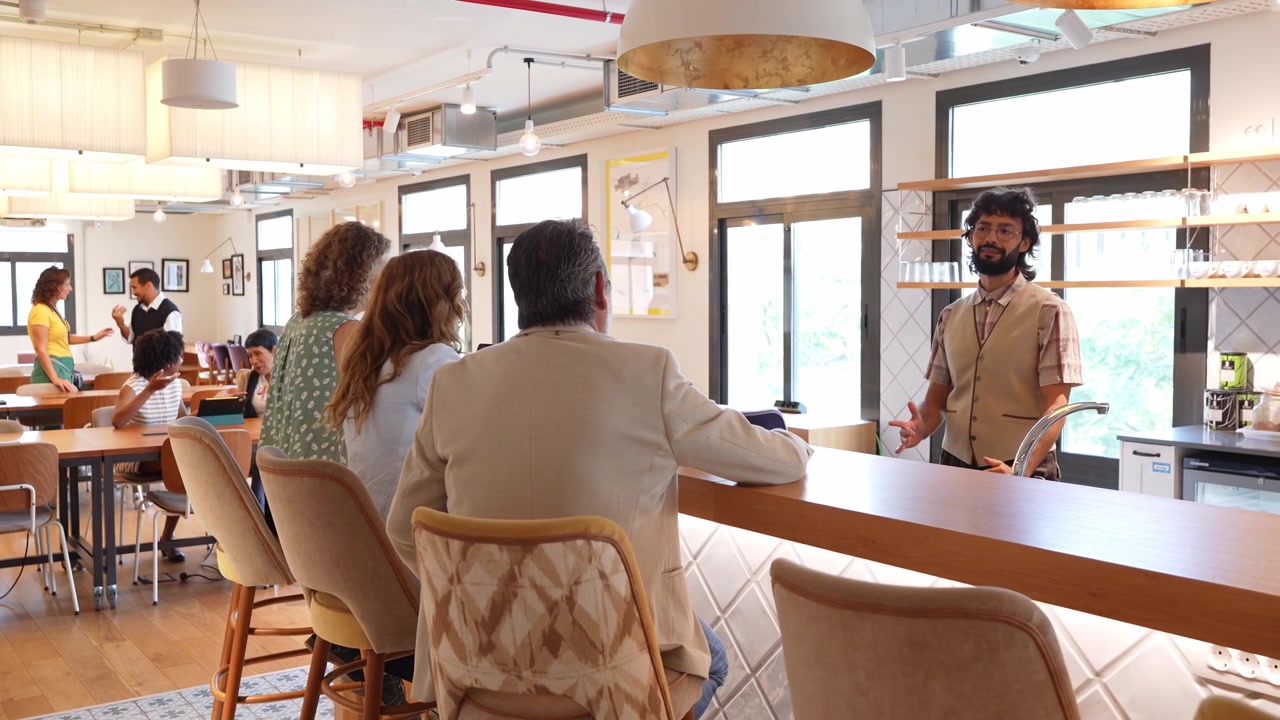 Barista conversando com clientes no balcão de uma cafeteria moderna.