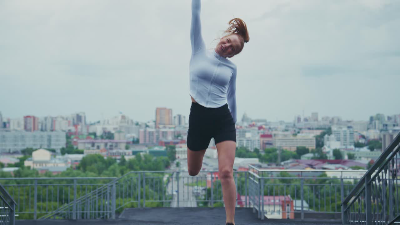 Woman exercising on rooftop overlooking city