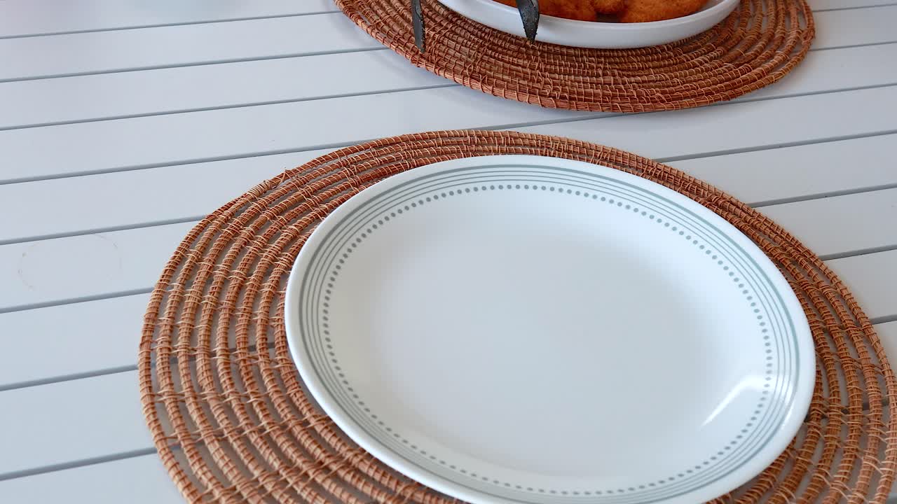 A table is set with plates and cutlery for a fried chicken meal. Bright lighting and a casual setting enhance the inviting atmosphere