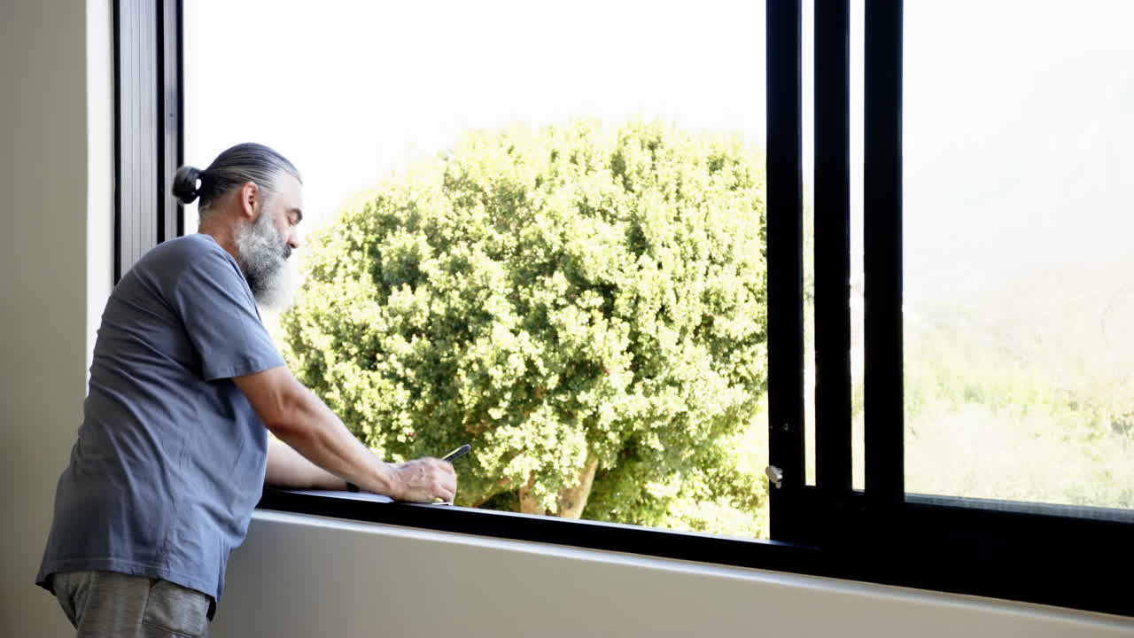 Using tablet, senior man working from home near open window, copy space