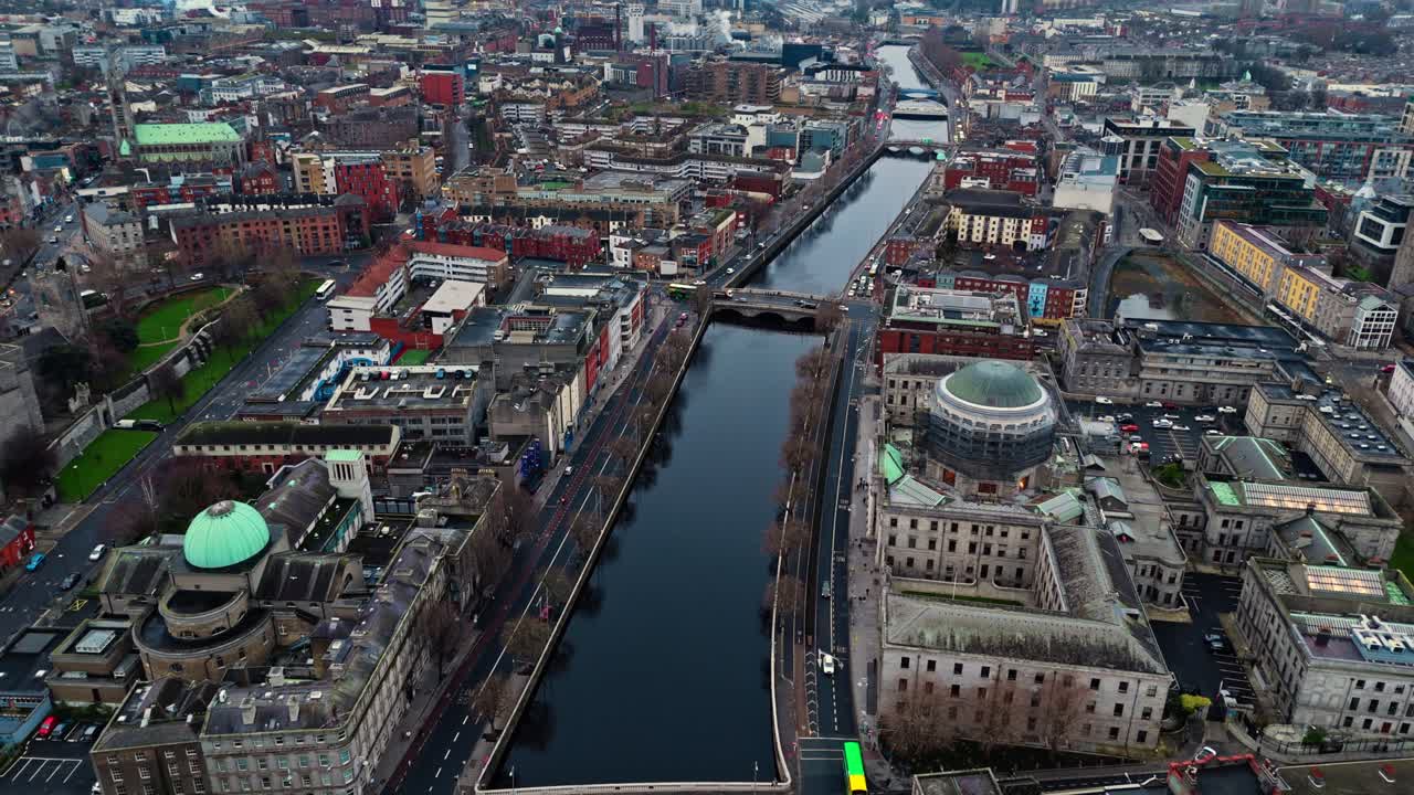 Luftaufnahme mit einer Drohne der irischen Hauptstadt Dublin mit belebten Straßen voller Verkehr und TouristInnen, die bei Sonnenaufgang im Winter durch die leuchtenden Straßen mit irischer Architektur laufen