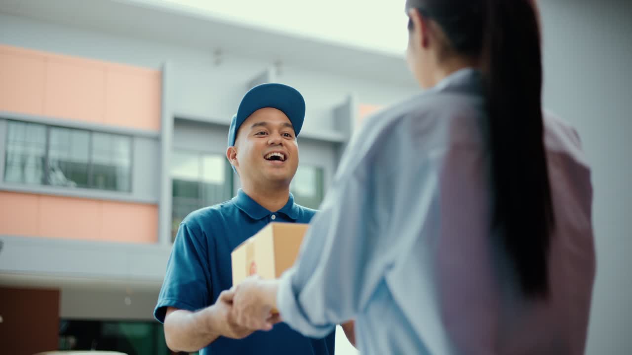 Blue uniform delivery man send parcel to customer front of the house with good service from shopping online. Courier man delivering a cardboard box postal package to destination.