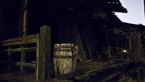 Old wooden building with a barrel on the porch at twilight
