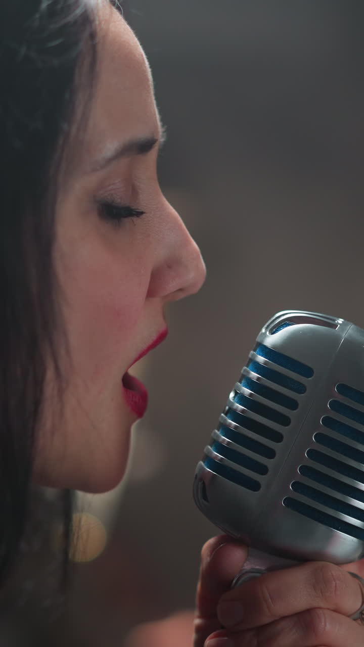 깊은 감정으로 노래하는 열정적인 여성 보컬리스트, 빈티지 마이크를 들고, 흐릿한 배경을 배경으로, 그녀의 강렬하고 진지한 공연을 강조합니다.