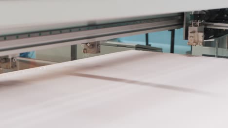 a close-up of a computer-aided machine applying automatic glue to foam for the manufacture of a mattress in a textile factory