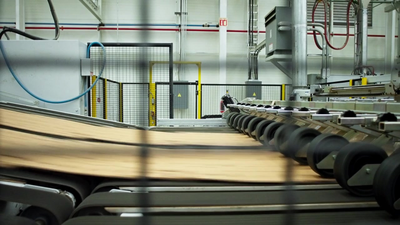 Cardboard sheets moving along automated conveyor system inside modern packaging factory, zoom out