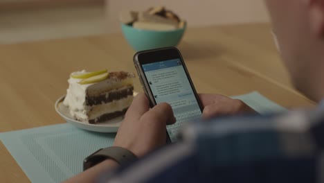 persona que usa un teléfono inteligente mientras disfruta de un pastel