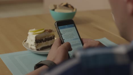 person using a smartphone while enjoying a cake