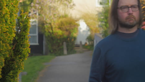 Thoughtful-man-walks-into-focus-and-past-along-neighorhood-path