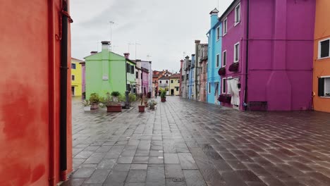 burano paved street with colourful painted houses on wet day, slow pov