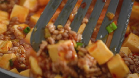 cooking mapo tofu. stir-frying tofu with hot spicy sauce in a pot at home.