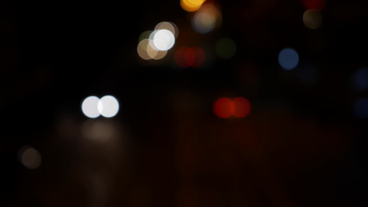 hermoso bokeh brillante en el fondo oscuro borroso por la noche. el redondo bokeh colorido brilla de las luces de los coches en la calle de la ciudad. fuera de foco con borroso. luces de la ciudad sin enfoque. bokeh de tráfico. concepto abstracto