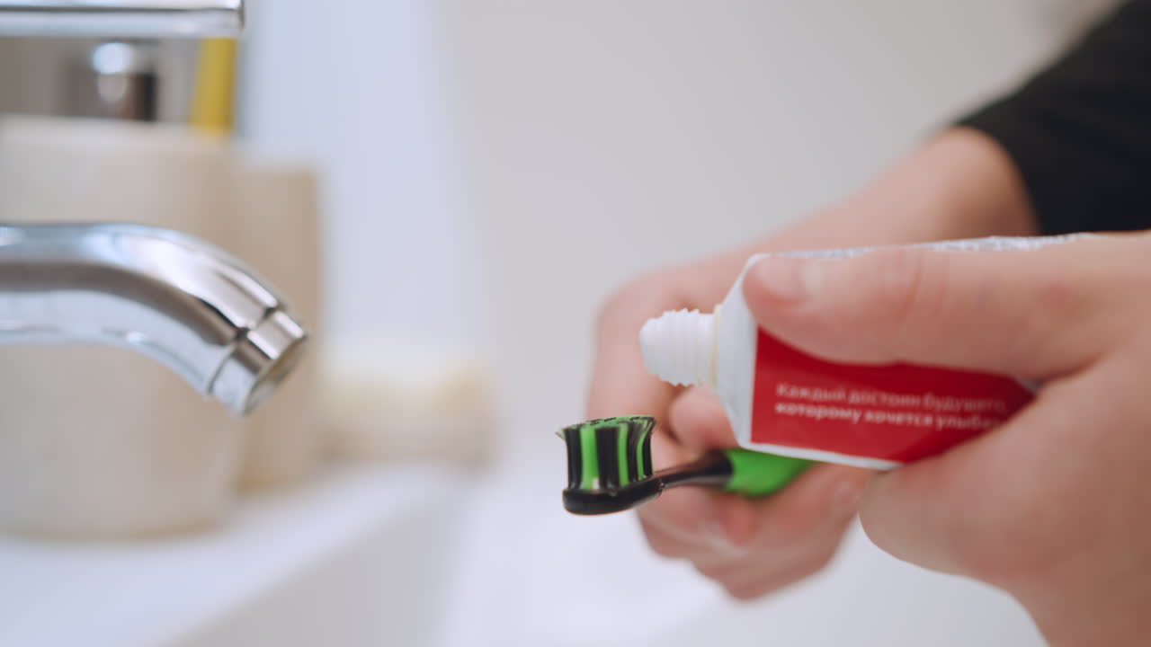 Hands brushing teeth. Playful scene of brushing teeth properly demonstrated. Interactive moment showcasing how to properly apply toothpaste to toothbrush in cheerful bathroom environment