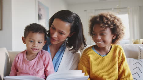 Afroamerikanische-Mutter-Sitzt-Auf-Dem-Sofa-Und-Liest-Ihren-Beiden-Kindern-Vor,-Vorderansicht,-Nahaufnahme