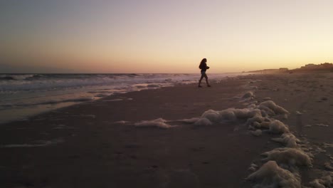 Wide-shot-silhouette-of-girl-taking-photos-at-the-beach-during-sunset