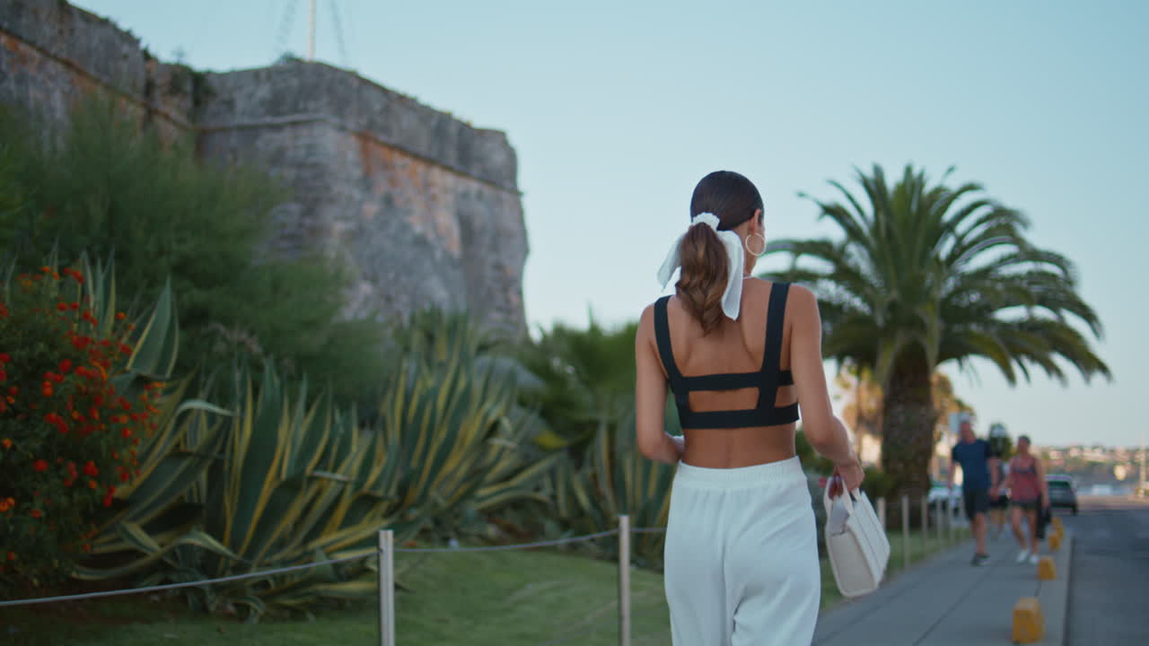 mujer caminando en una ciudad con vista a la fortaleza