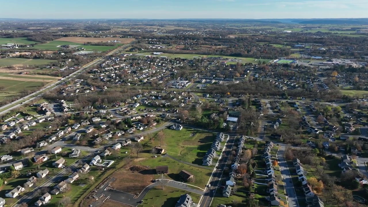 Inquadratura aerea di apertura di un paesaggio rurale con zona residenziale americana e autostrada interstatale trafficata a Elizabethtown, Pennsylvania. Campo lungo. Campi agricoli al tramonto.