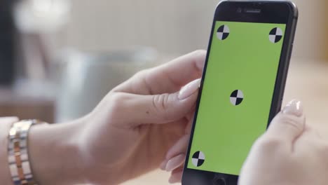 woman holding smartphone with green screen and calibration markers