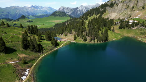 aerial: lake lioson during the day with restaurant in ormont-dessous, near les mosses, in the canton of vaud, switzerland, orbit drone shot