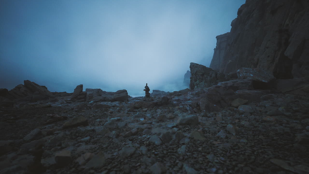 Lonely figure standing amidst rocky landscape on a misty evening