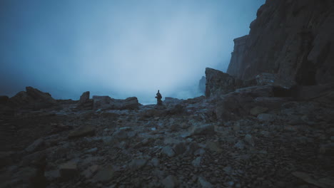 lonely figure standing amidst rocky landscape on a misty evening