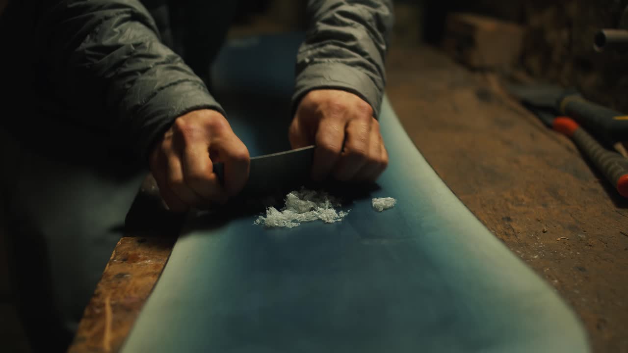 Close up scraping wax of a snowboard