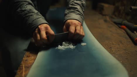 cerrar raspando la cera de una tabla de snowboard