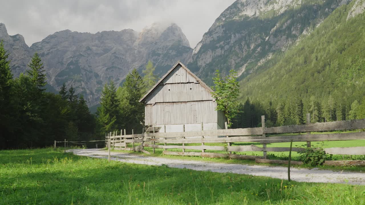Una coppia fa un'escursione oltre un'antica fattoria nella pittoresca valle di Robanov Kot circondata dalle montagne.