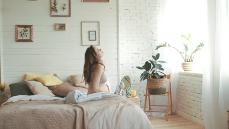 Mujer-Embarazada-Levantándose-En-El-Dormitorio.-Futura-Madre-Acariciando-El-Vientre-En-Casa